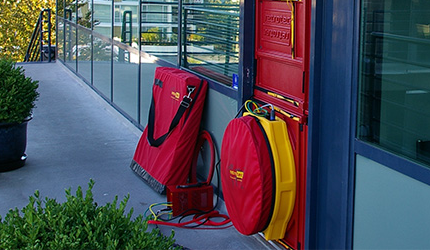 Red door with a yellow bag placed against it for Enclosure Integrity Testing by fire protection services Perth, ensuring airtight room seals