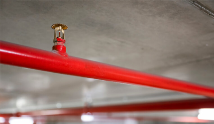 Red pipe with metal cap on neutral wall, essential to Fire Suppression Systems, installed by expert fire sprinkler service WA contractor