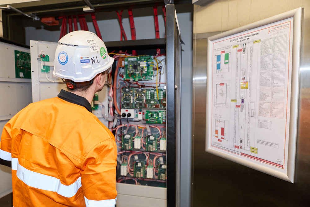 A man in an orange vest and hard hat is conducting a room integrity testing